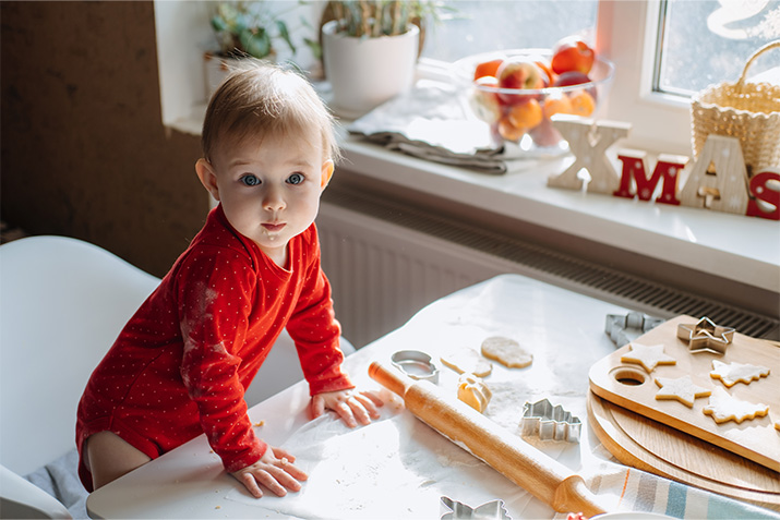 Baby is helping bake Christmas cookies to start a new family tradition, celebrating their first family Christmas. 